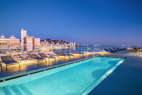 Una piscina al aire libre, sombrillas, sillones reclinables de piscina