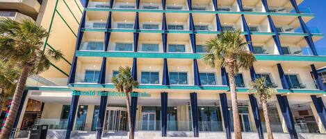 Un hotel de varios pisos con diseño moderno, que cuenta con balcones y un atrio central.