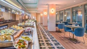 Ein Buffetbereich mit verschiedenen Speisen und eine Sitzgelegenheit mit Tischen und Stühlen.