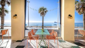 A table and chairs in a room with a view of the beach and ocean.