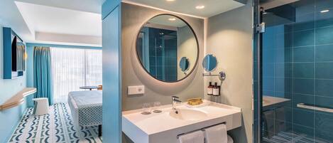 Un baño moderno con un espejo grande, un lavabo blanco y una zona de ducha.