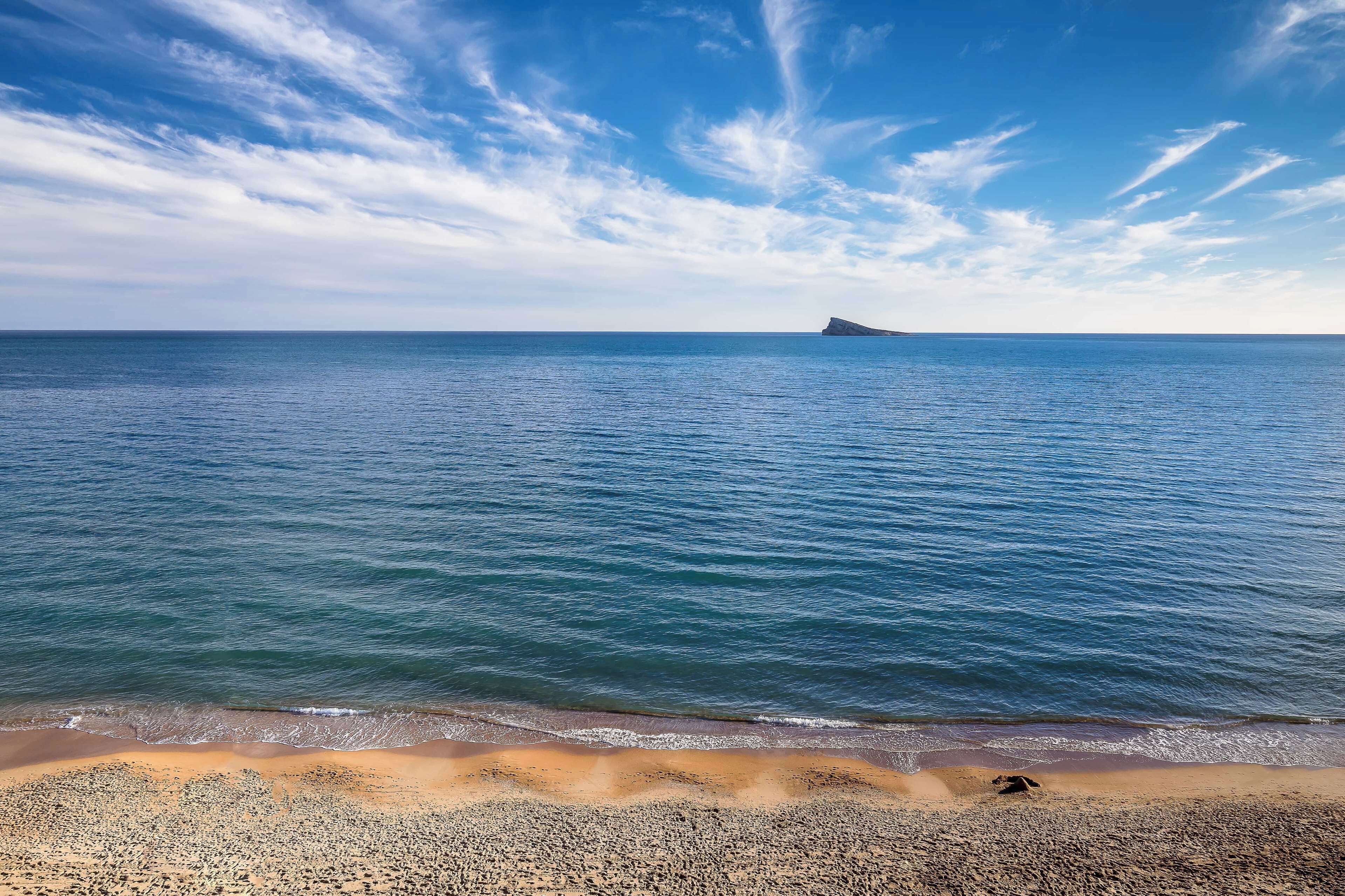 Een strand met heldere lucht en rustig water.