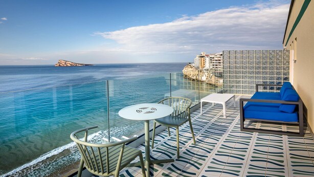 Un balcón con vistas despejadas al mar, una mesa blanca y un sofá azul.