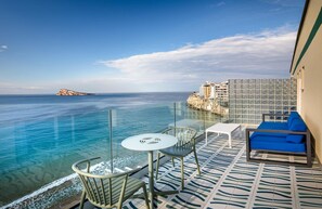 Un balcón con vistas despejadas al mar, una mesa blanca y un sofá azul.