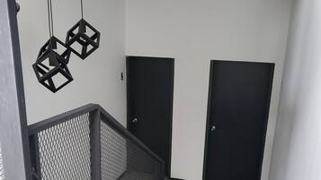 Un interior moderno con una escalera, puertas negras y una lámpara en el techo.