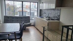 Una cocina moderna con comedor, que incluye un sofá, mesa de comedor, sillas y una encimera con fregadero y salpicadero de azulejos.