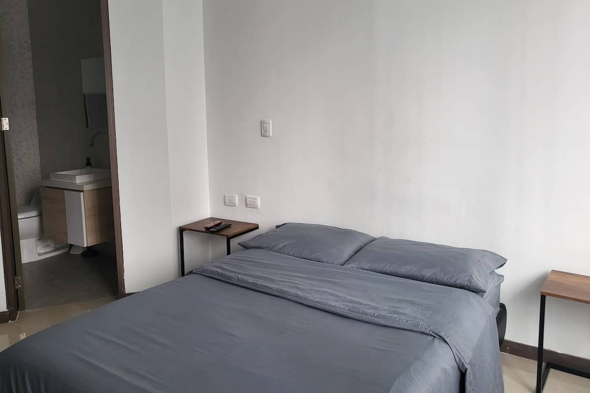 A minimalist bedroom with a bed, a nightstand, and a small table.