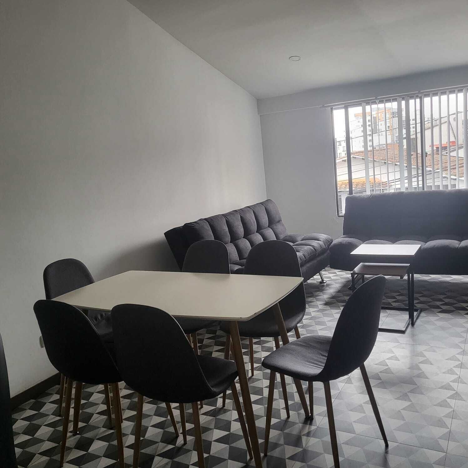 A modern room with a sofa, a dining table, and chairs.