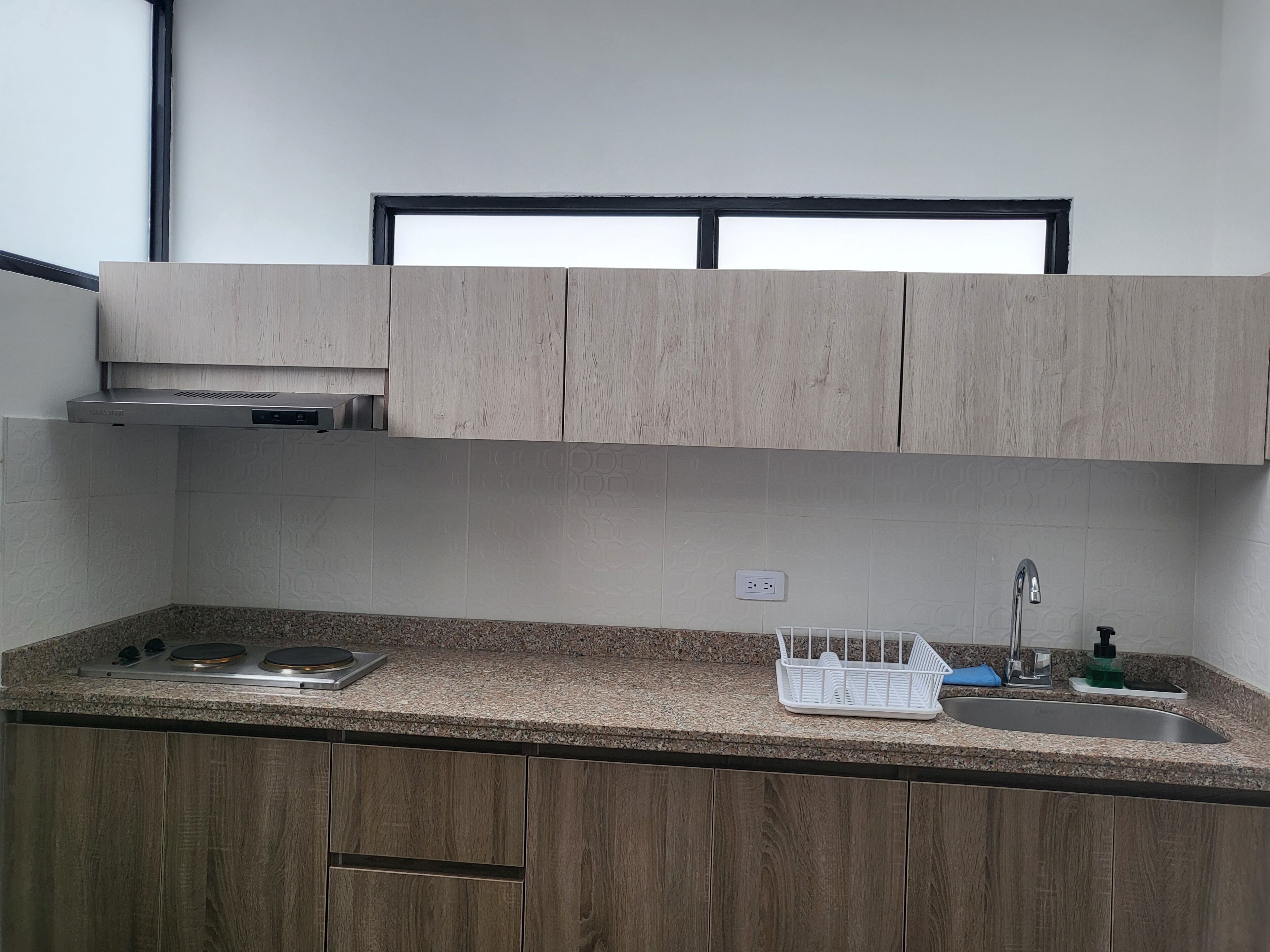 A kitchen with wooden cabinets, a granite countertop, a stainless steel sink, and a dish rack.