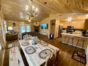 Interior de una cabaña con comedor, cocina, sala de estar y chimenea.