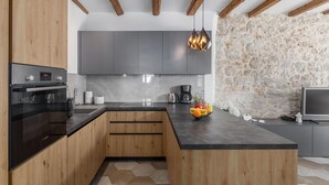 Una cucina moderna con mobili in legno, un'isola centrale e una parete in pietra.