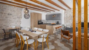 Una cucina moderna con travi in legno, un muro in pietra e un'area pranzo con tavolo e sedie in legno.