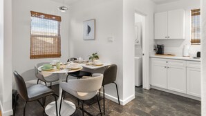 A modern kitchen with white cabinets, a dining area with a round table and chairs, and a visible dishwasher. - Central Phx Kid/Pet friendly home next to Banner Hospital & Historic Coronado (Phoenix)