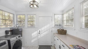 A laundry room with a washing machine, a sink, and a door. - Forest Hills Cottage - 4.2 Miles from Masters (Augusta)