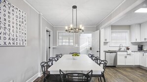 A modern kitchen with white cabinets, a central island, and a chandelier. - Forest Hills Cottage - 4.2 Miles from Masters (Augusta)