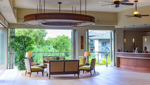 A spacious lobby with a reception desk, seating area, and large windows offering a view of greenery.