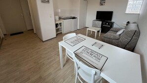 Un espace de vie compact comprenant un coin cuisine, un coin repas et un coin salon.