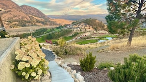 A stone pathway leading to a scenic view of a village with mountains in the background. - 
Oasis @ Black Mountain - Only 25 mins to Big White (Kelowna)
