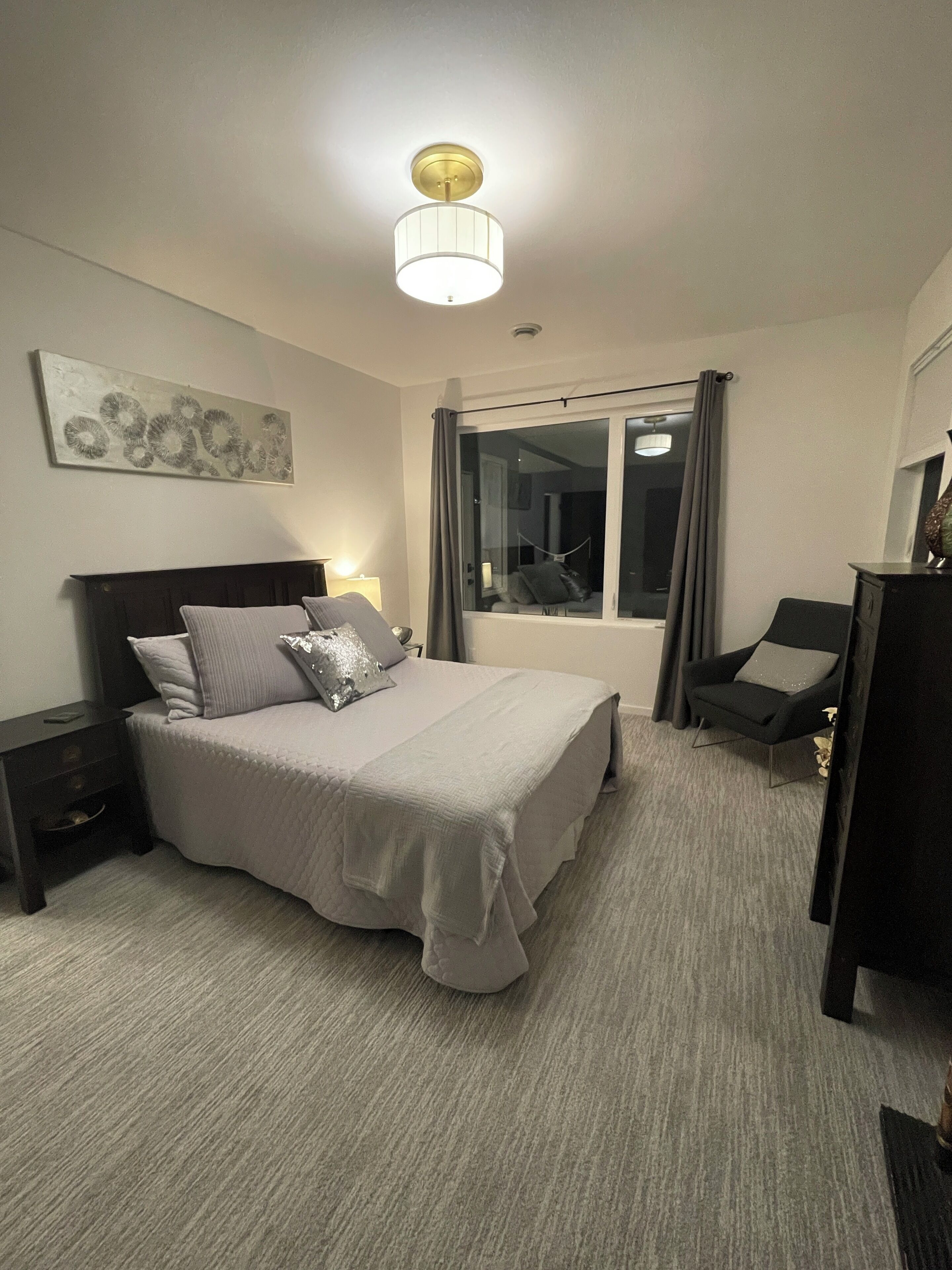 Habitación de hotel ordenada con cama, mesitas de noche, escritorio y ventana con cortinas.