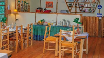 Un ristorante con mobili in legno, una tovaglia verde e una varietà di piatti e bevande sul tavolo.