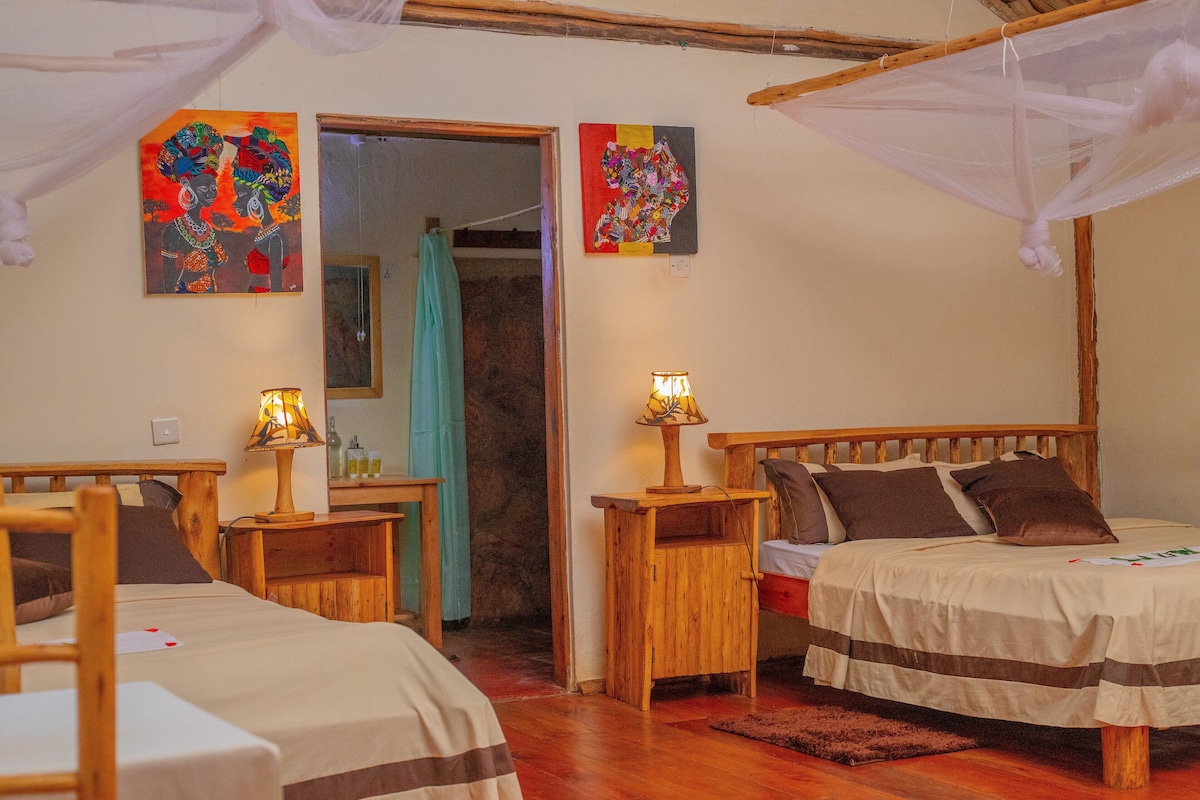 A room with two wooden beds, a nightstand with a lamp, and artwork on the walls.