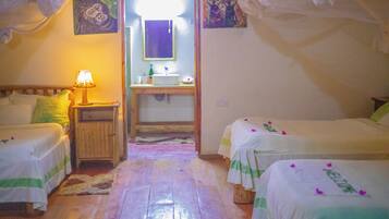 Una habitación con dos camas, una mesita de noche con lámpara, un baño con lavamanos y espejo.