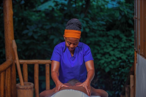 A person performing a massage on another individual seated on a massage table.