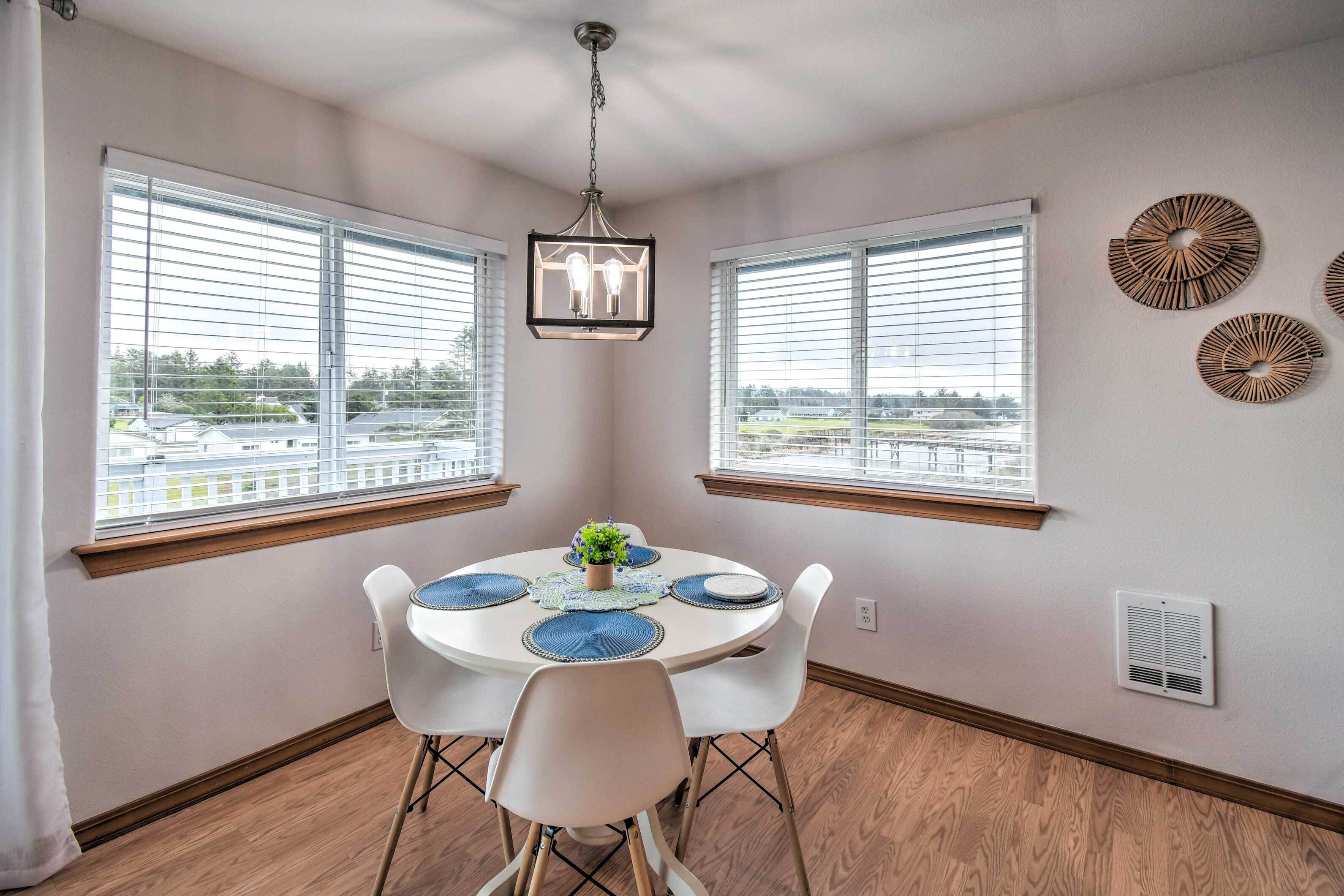 A dining area with a round table, white chairs, and a hanging light fixture.