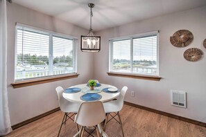 A dining area with a round table, white chairs, and a hanging light fixture. - Canal-Front Vacation Rental in Ocean Shores (Ocean Shores)