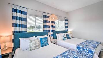 Une chambre d’hôtel avec deux lits, des rideaux à rayures, un luminaire suspendu et une vue sur l’extérieur.