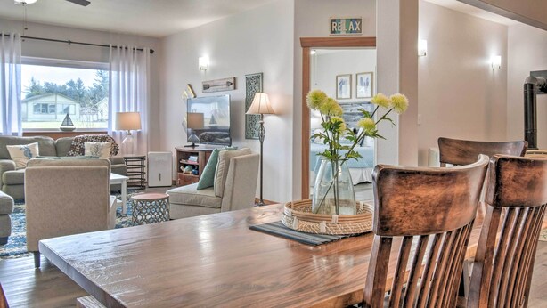 Ein Wohnzimmer mit einem Holzesstisch, Stühlen, einem Fernseher und einer Vase mit Blumen.