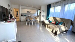Una sala de estar moderna con un sofá, una mesa de comedor y una zona de cocina al fondo.