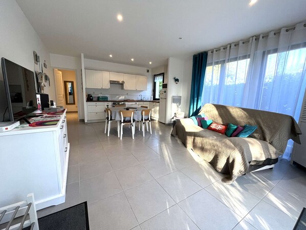 Una sala de estar moderna con un sofá, una mesa de comedor y una zona de cocina al fondo.