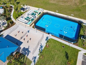 Een overzicht vanuit de lucht van een sportcomplex met een basketbalveld, een tennisbaan en een zwembad.