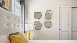 Et hotelværelse med en seng, et natbord, en lampe og en dør.