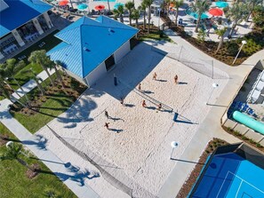 A beach volleyball court with a blue-roofed building adjacent to it. - Themed family retreat with epic game room (Davenport)