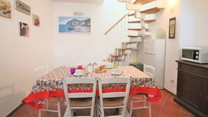 A dining area with a table set for four, a staircase, and a kitchen area with a microwave.