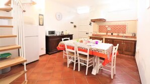A kitchen with a dining table, chairs, and a staircase.