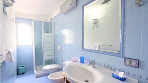 A bathroom with a shower, toilet, sink, and a large mirror.