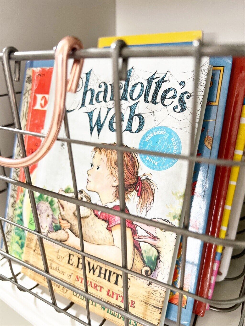 A metal rack holding books, including 'Charlotte's Web' by E.B. White.