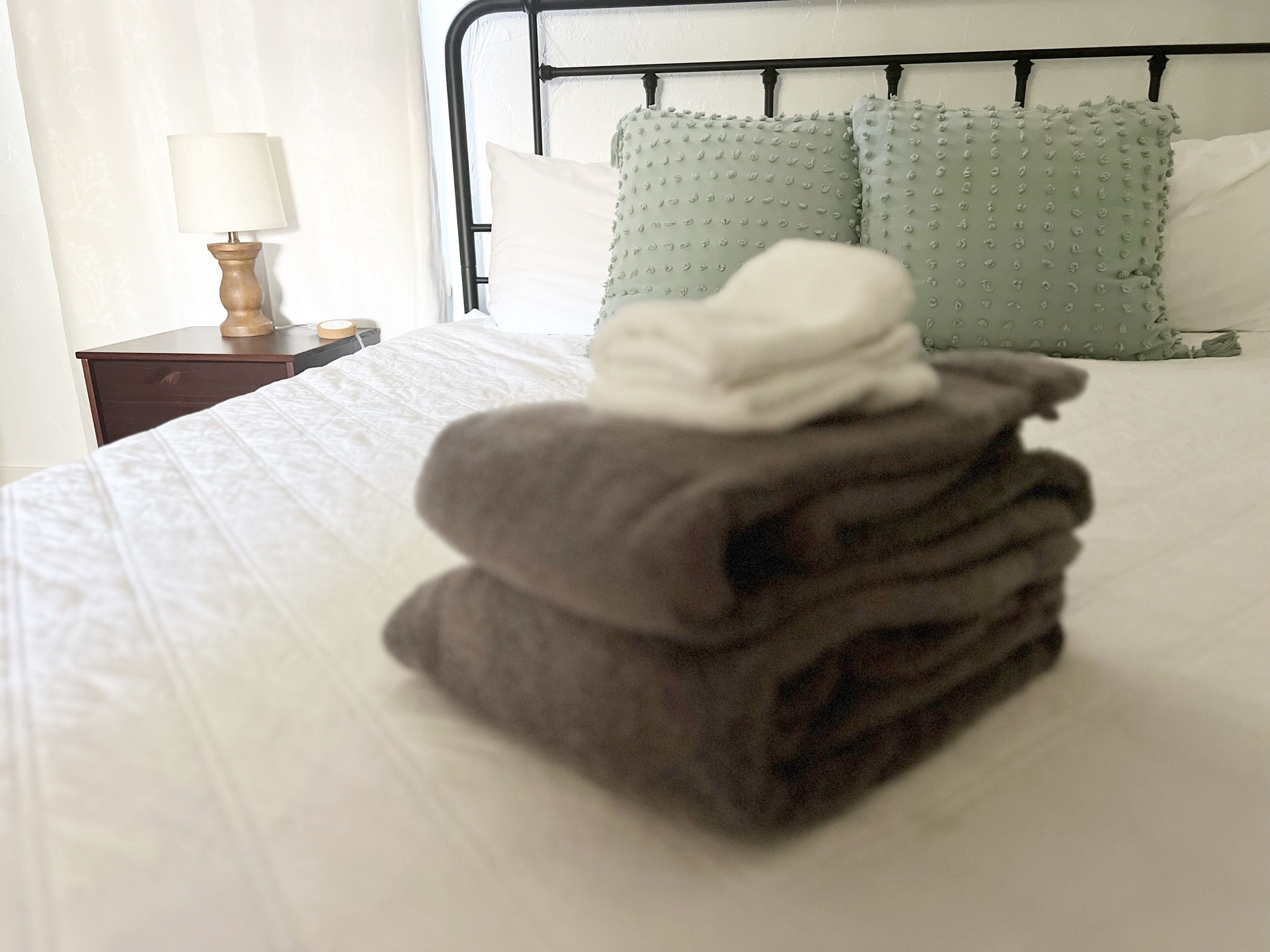 Una cama bien hecha con una pila de toallas dobladas en el centro.