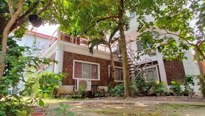 A two-story building with a balcony, surrounded by lush greenery. - OYO 799 Ddd Habitat Iloilo (Iloilo)