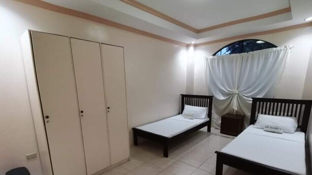 A bedroom with two single beds, a wardrobe, and a small trash bin. - OYO 799 Ddd Habitat Iloilo (Iloilo)