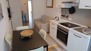Une cuisine compacte comprenant une table à manger, des chaises, un canapé et un petit coin cuisine.