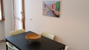 Un coin repas avec une table noire, deux chaises et un panier en osier.