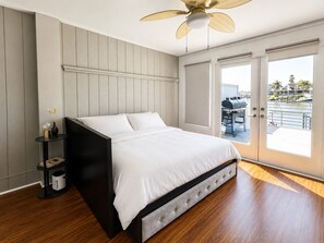 A bedroom with a bed, a side table, a ceiling fan, and a view of the outside. - Paradise Home in Discovery Bay minutes to fast water (Discovery Bay)
