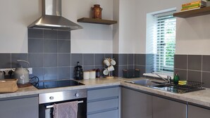 Una cocina moderna con baldosas grises, electrodomésticos de acero inoxidable y un ventanal con persianas.