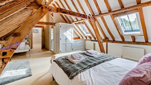 A bedroom with a sloped ceiling, a bed, a window, and a wardrobe. - Court Lodge is a substantial and picturesque twin roundel oast house set in pretty gardens within th (Heathfield)