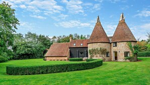 A traditional brick house with two conical towers and a well-maintained lawn. - Court Lodge is a substantial and picturesque twin roundel oast house set in pretty gardens within th (Heathfield)
