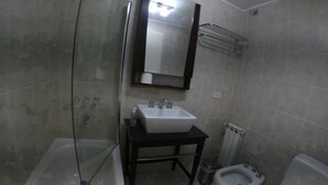A bathroom with a glass shower enclosure, a sink, a toilet, and a bidet. - Duerme Ushuaia (Ushuaia)